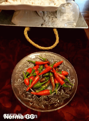 A Glass Plate Filled With Red And Green Peppers With Norma Gg Written On The Bottom GIF