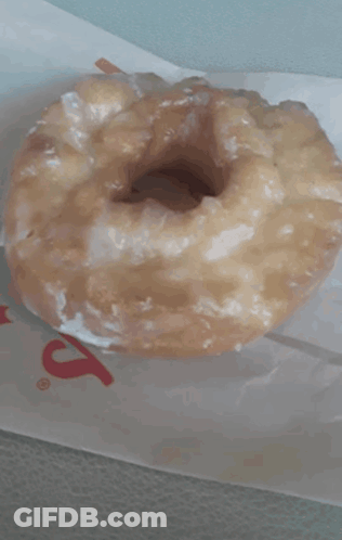 A Glazed Donut Is Sitting On A Piece Of Paper That Says ' S ' On It GIF