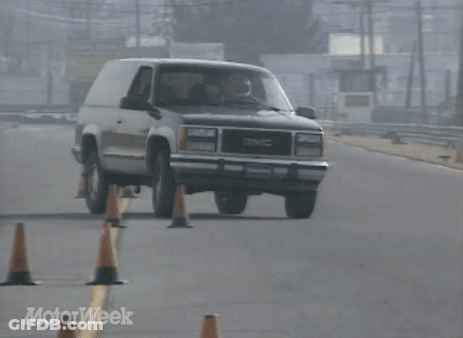 A Gmc Suv Is Driving Down A Road Surrounded By Orange Cones GIF