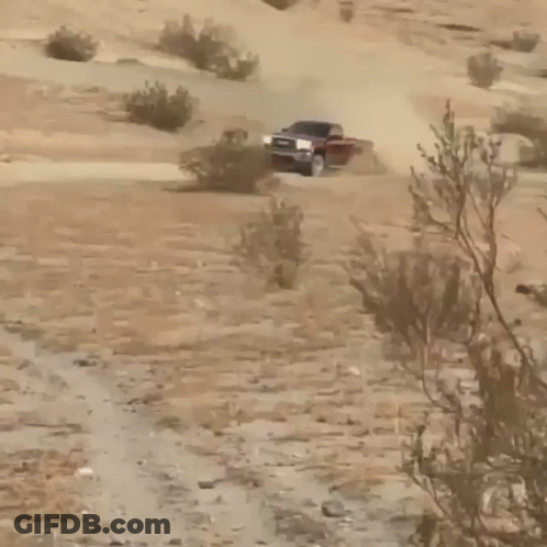 A Gmc Truck Driving Down A Dirt Road GIF