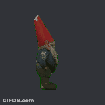 A Gnome With A Beard And A Red Hat Is Standing On A Dark Background GIF