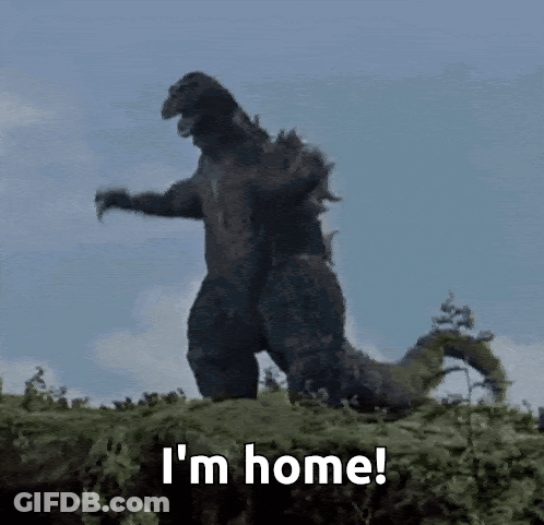 A Godzilla Is Standing On Top Of A Pile Of Grass And Says I 'M Home . GIF