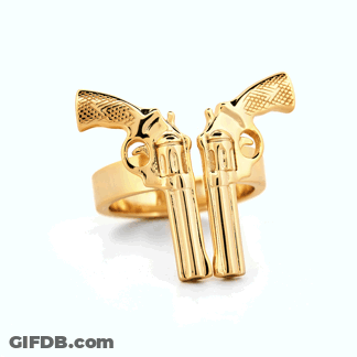 A Gold Ring With Two Guns On It On A White Surface GIF