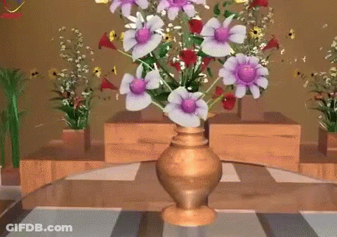 A Gold Vase Filled With Purple And White Flowers Sits On A Table GIF