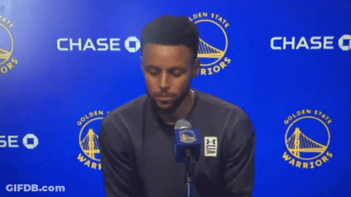 A Golden State Warriors Player Stands In Front Of A Chase Sign GIF