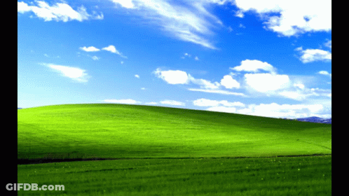 A Grassy Hill With A Blue Sky And White Clouds GIF