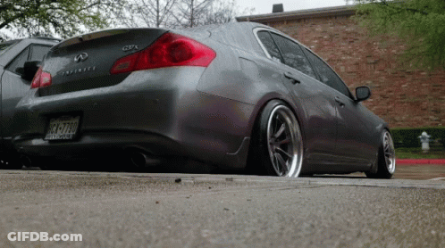 A Gray Infiniti Is Parked On The Side Of A Road GIF