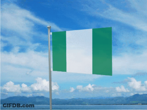 A Green And White Flag Is Flying In The Wind With Mountains In The Background GIF