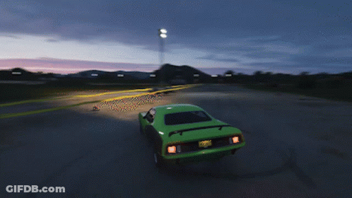 A Green Car Is Driving Down A Road With A Sunset In The Background GIF