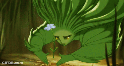 A Green Cartoon Character Is Holding A Small Flower GIF