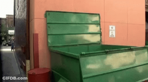 A Green Dumpster Is Sitting On The Side Of A Building GIF