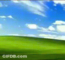 A Green Field With A Blue Sky And Clouds Behind It GIF