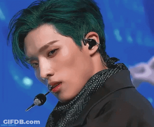 A Green Fish Is Swimming In The Water With A Person In The Background GIF