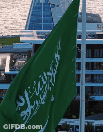 A Green Flag With Arabic Writing On It Flies In Front Of A Building GIF