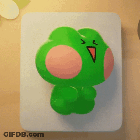A Green Frog With A Red Beak Is Sitting On A Table GIF