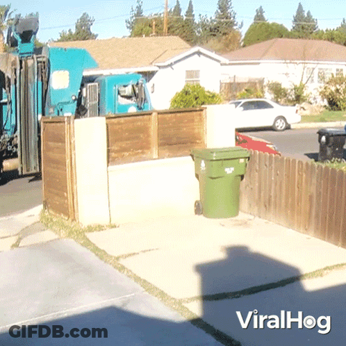 A Green Garbage Can Sits In Front Of A Wooden Fence With A Viralhog Logo On The Bottom GIF