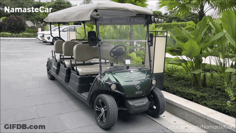 A Green Golf Cart Is Parked On A Sidewalk With The Words Namaste Car Written On The Bottom GIF