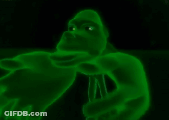 A Green Gorilla With Glowing Eyes Is Holding A Microphone In The Dark . GIF