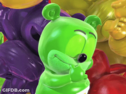 A Green Gummy Bear Standing In Front Of A Pile Of Gummy Bears GIF