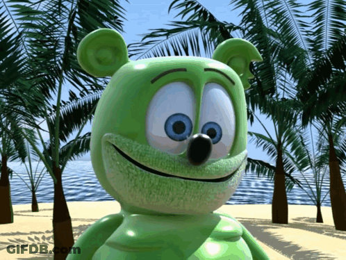 A Green Gummy Bear With Blue Eyes Is Standing On A Beach GIF