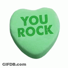 A Green Heart Shaped Candy With The Words `` You Rock '' Written On It . GIF