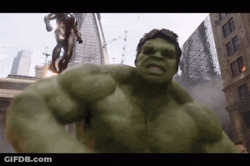 A Green Hulk Is Standing In Front Of A Statue Of A Man GIF