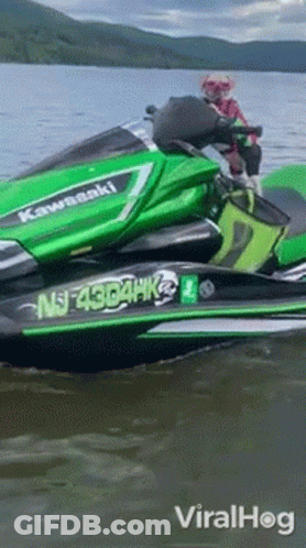 A Green Kawasaki Jet Ski Is Floating On The Water GIF