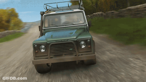 A Green Land Rover Is Driving Down A Dirt Road With Trees In The Background GIF