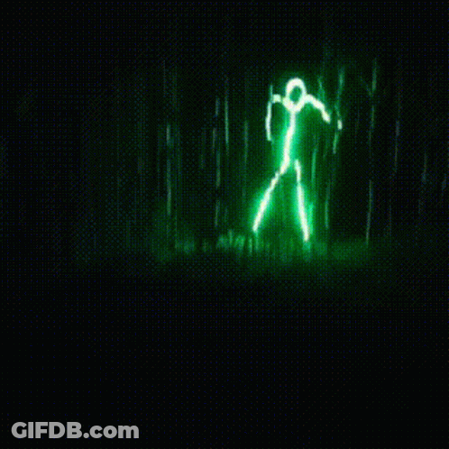 A Green Light That Looks Like A Person Standing In A Forest GIF