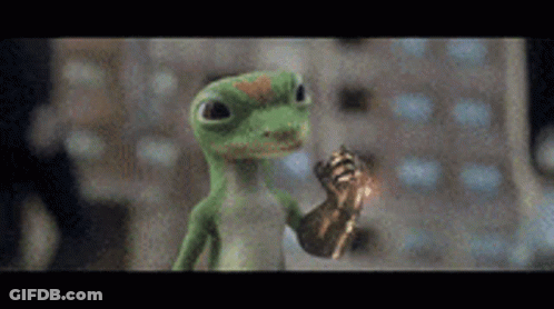 A Green Lizard Is Holding A Gold Object In Its Hand And Giving A Thumbs Up . GIF
