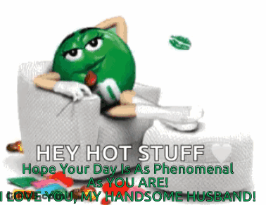 A Green M & M Sitting In A Chair With A Rose In His Mouth GIF