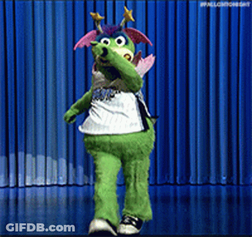 A Green Mascot Is Dancing On A Stage With A Blue Curtain Behind Him GIF