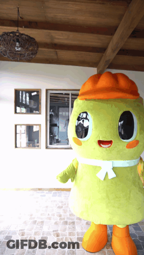 A Green Mascot Wearing An Orange Hat And Orange Feet GIF