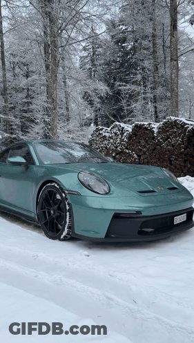 A Green Porsche 911 Gt3 Is Parked In The Snow . GIF