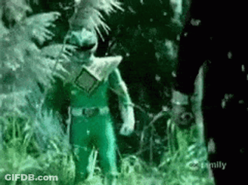 A Green Power Ranger Is Standing In The Grass Next To A Man . GIF