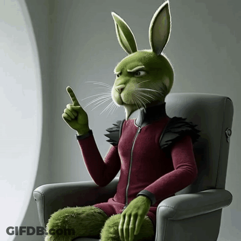 A Green Rabbit Is Sitting In A Chair And Pointing Upwards GIF