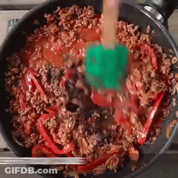 A Green Spatula Is Stirring A Pan Of Food GIF