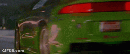 A Green Sports Car Is Driving Down A Street And Has The Word Turbo On The Hood GIF