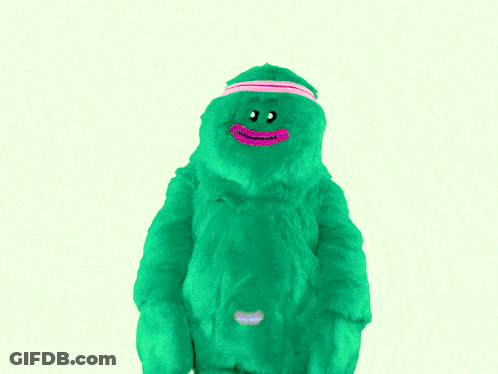 A Green Stuffed Animal Is Wearing A Pink Headband With The Word Muah On It GIF