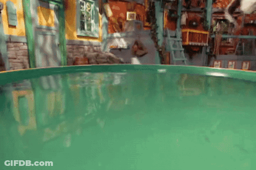A Green Swimming Pool In A Room With A Ladder GIF
