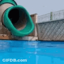 A Green Tube Is Going Down A Water Slide Into A Pool GIF