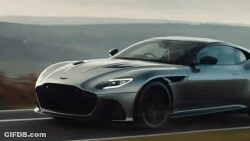A Grey Sports Car Is Driving Down A Road GIF