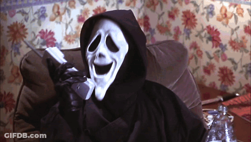 A Grim Reaper Talking On A Cell Phone In Front Of A Floral Wall GIF