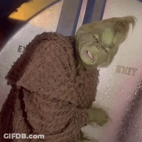 A Grinch Is Standing In Front Of A Glass Door That Says Exit GIF