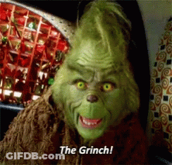 A Grinch Says " The Grinch " In Front Of A Display Of Christmas Decorations GIF