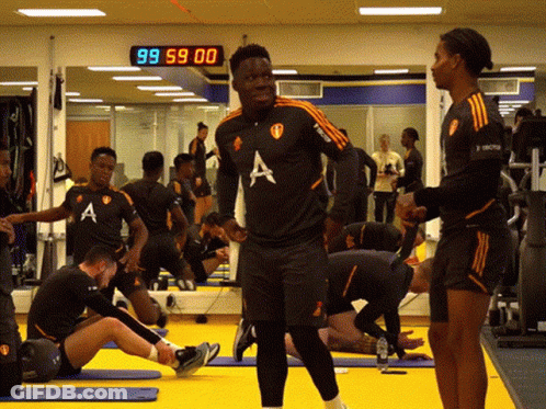 A Group Of Athletes Are In A Gym With A Clock That Says 99 59 00 GIF