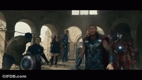 A Group Of Avengers Are Standing In A Room . GIF