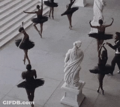 A Group Of Ballerinas In Black Tutus Are Dancing In Front Of A Statue GIF