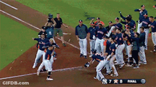 A Group Of Baseball Players Are Celebrating On The Field With A Scoreboard That Says Final GIF