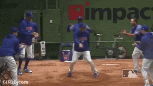 A Group Of Baseball Players Are Dancing In Front Of A Green Wall That Says Impact GIF